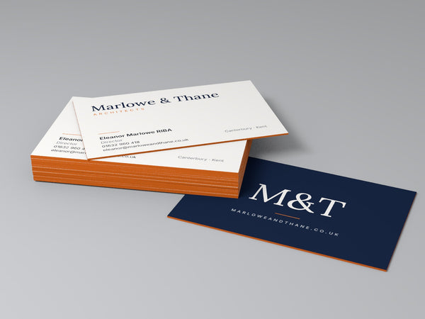 600gsm coloured edge business cards with orange edges, stacked on a grey surface